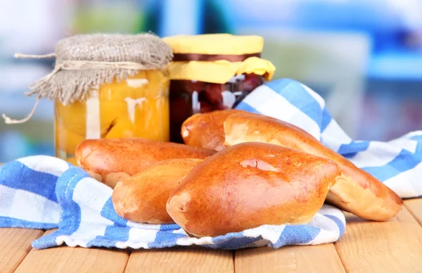 Pasticcini appena sfornati con marmellata di frutta, su tavolo di legno, su sfondo brillante — Foto Stock