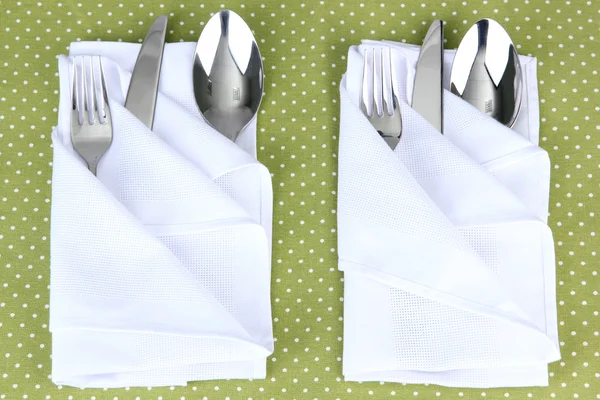 Folded napkin with fork, spoon and knife on color background — Stock Photo, Image