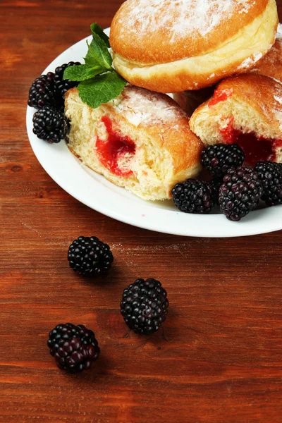 Leckere Donuts mit Beeren auf Holztisch — Stockfoto