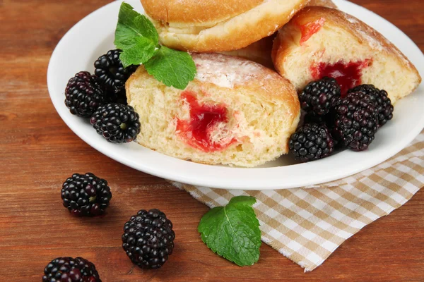 Leckere Donuts mit Beeren auf Holztisch — Stockfoto