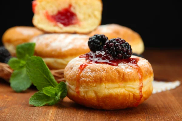 Tasty donuts with berries on wooden table — Stock Photo, Image