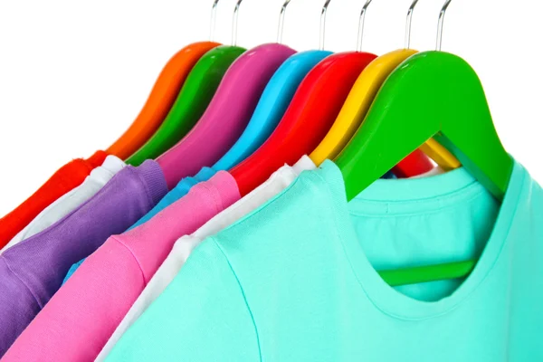 Different shirts on colorful hangers on white background — Stock Photo, Image