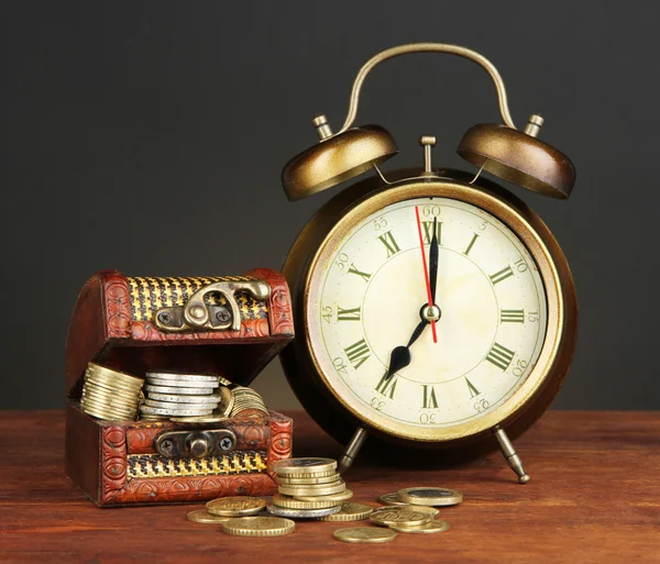 Антикварные часы и монеты на деревянном столе на черном фоне — стоковое фото