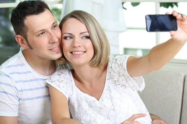 Young couple taking photo with mobile phone in restaurant — Stock Photo, Image