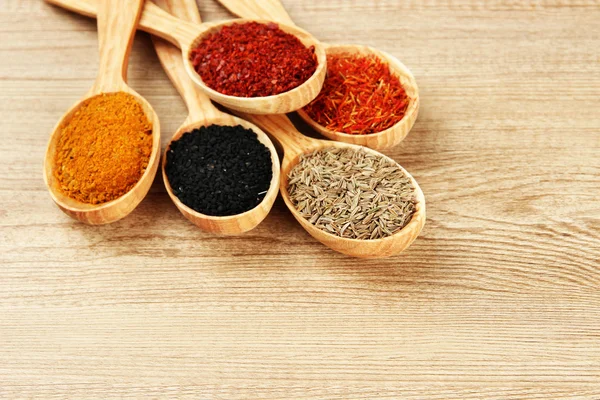 Assortment of spices in wooden spoons on wooden background — Stock Photo, Image