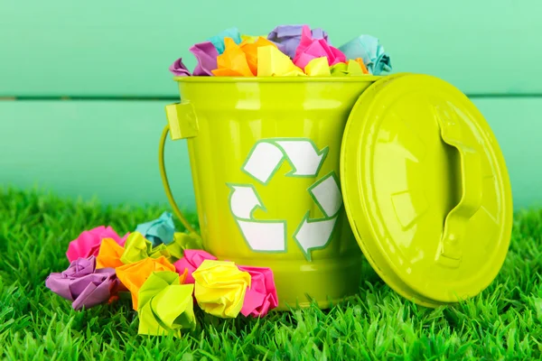 Reciclagem bin na grama verde na cor de fundo de madeira — Fotografia de Stock