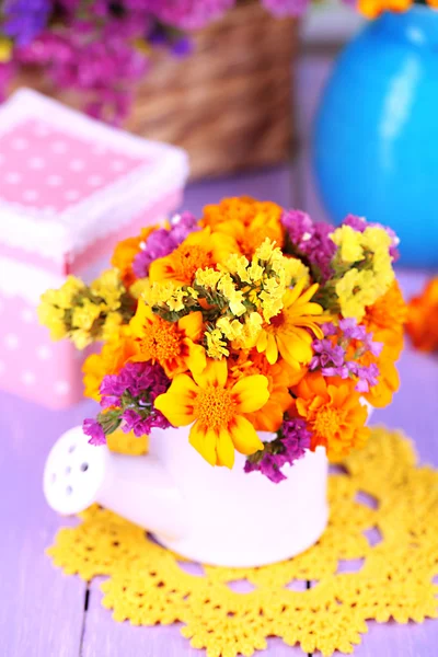 Bouquet of marigold flowers in watering can on wooden table close-up — Stock Photo, Image