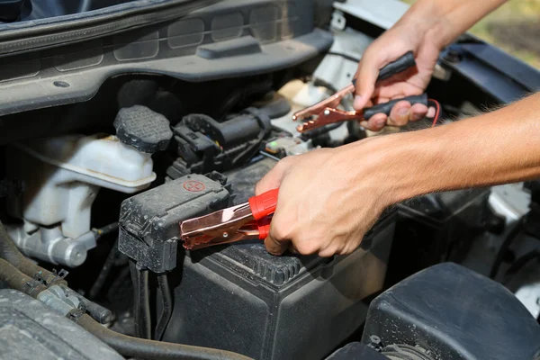 Carro mecânico usa cabos jumper bateria para carregar bateria morta — Fotografia de Stock