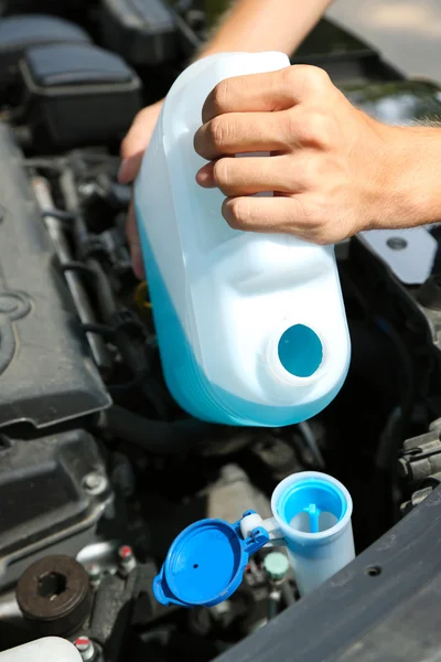 Man pours liquid for washing glasses to car — Stock Photo, Image