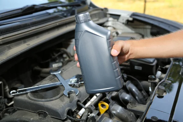 Automechaniker hält Motoröl in der Hand — Stockfoto