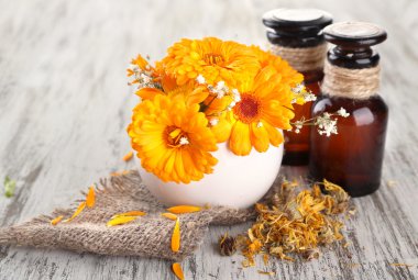 ilaç şişeleri ve ahşap zemin üzerine calendula çiçekler