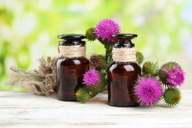 Medicine bottles with thistle flowers on nature background clipart