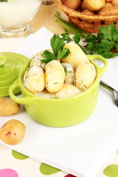 Jeunes pommes de terre tendres à la crème sure et aux herbes dans une casserole sur une table en bois close-up — Photo