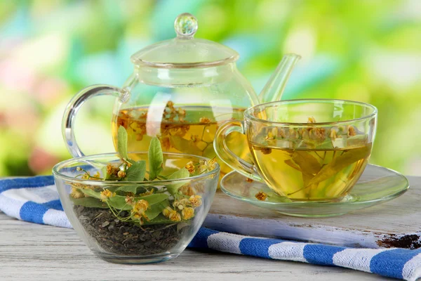 Waterkoker en kopje thee met linden op houten tafel op aard achtergrond — Stockfoto