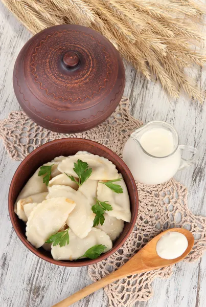 Tasty dumplings with fried onion on brown plate, on wooden background — Stock Photo, Image