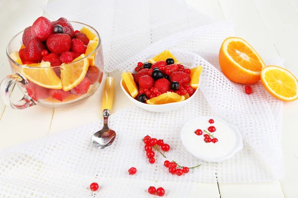 Salada de frutas útil em copo de vidro e tigela em mesa de madeira close-up — Fotografia de Stock