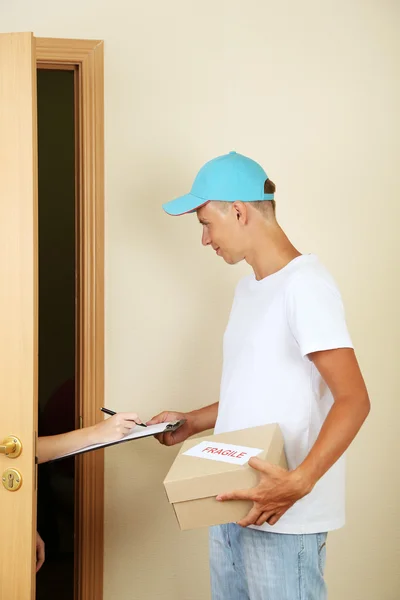 Junger Zusteller gibt Paket ab — Stockfoto