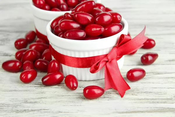 Fresh cornel berries in white cups on wooden table — Stock Photo, Image