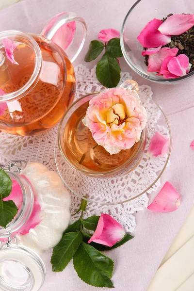 Wasserkocher und Tasse Tee aus Teerose auf Serviette auf Holzgrund — Stockfoto