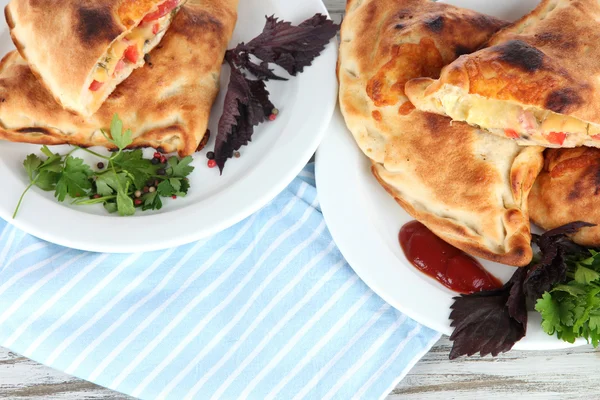 Pizza calzones on plates on napkin on wooden table — Stock Photo, Image