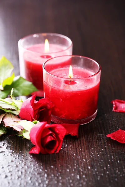 Belas velas vermelhas românticas com flores no fundo de madeira escura — Fotografia de Stock