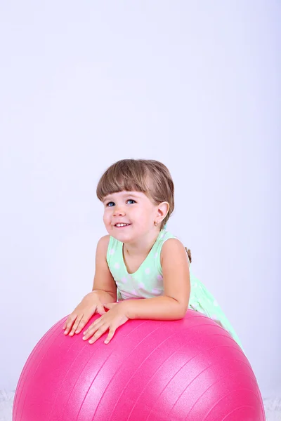 Niña linda jugando con bola grande, sobre fondo gris — Foto de Stock
