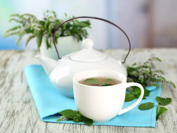 Teiera e tazza di tisana con fiori di menta freschi sul tavolo di legno — Foto Stock