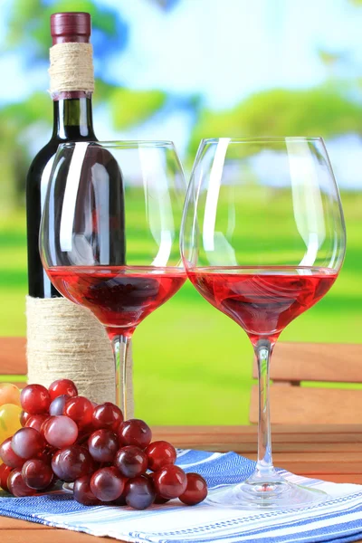 Sklenice vína na ubrousek na dřevěný stůl na pozadí přírody — Stock fotografie