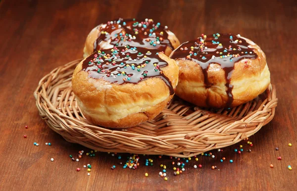 Donuts saborosos com chocolate na mesa de madeira — Fotografia de Stock