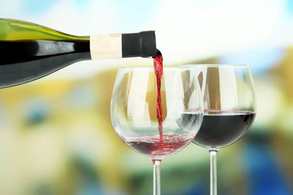 Red wine being poured into wine glass, on bright background — Stock Photo, Image