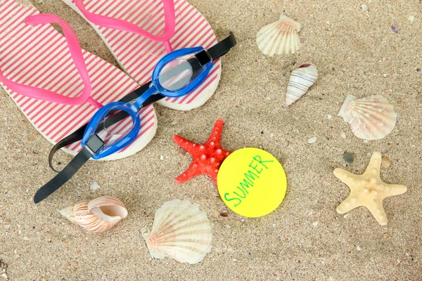 Composition with flip flops, goggles on sand background — Stock Photo, Image