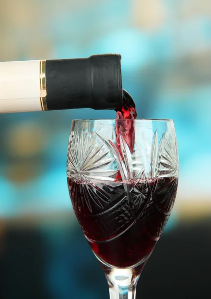 Rött vin som hälls i glas vin, på ljus bakgrund — Stockfoto