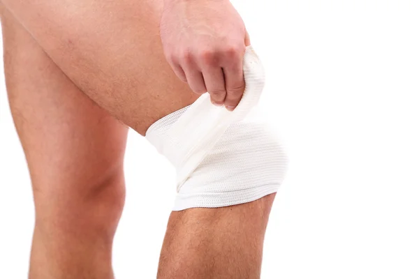 Young man with elastic bandage on knee, isolated on white — Stock Photo, Image