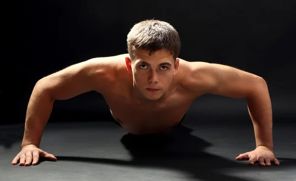 Guapo joven deportista muscular, sobre fondo oscuro — Foto de Stock