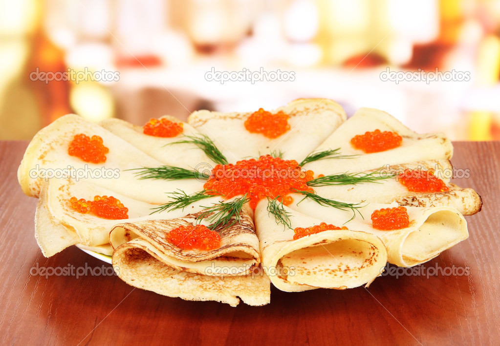 Delicious pancakes with red caviar on table in cafe