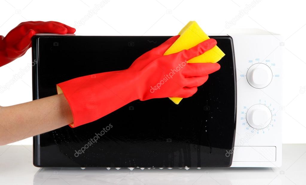 Hand with sponge cleaning microwave oven, isolated on white