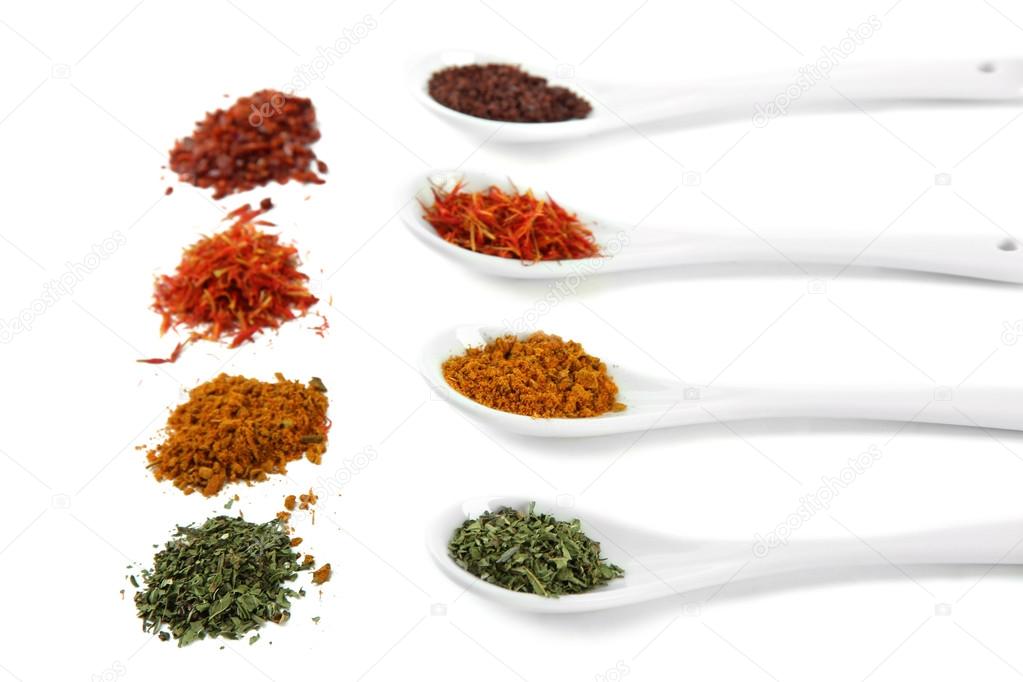 Assortment of spices in white spoons, isolated on white