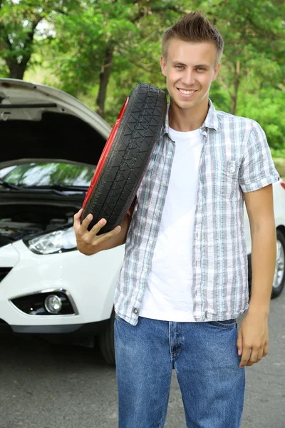 Homem motorista segurando pneu no ombro — Fotografia de Stock