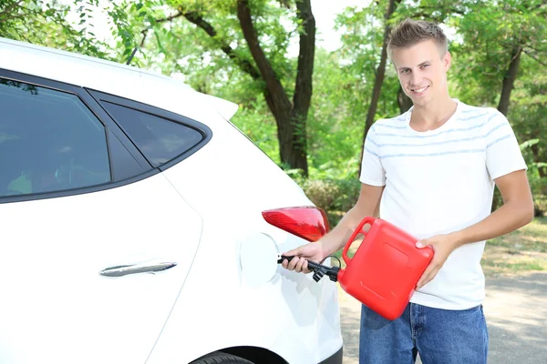 Man pouring fuel into gas tank of his car from red gas canister — Stock Photo, Image