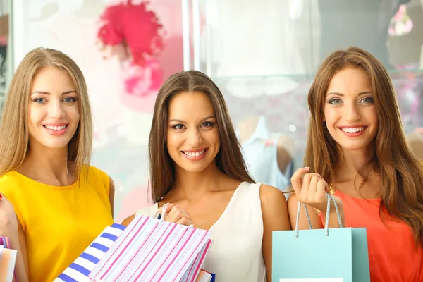 Tres hermosa mujer joven en la tienda con bolsas de compras —  Fotos de Stock