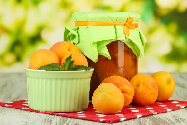 Aprikos sylt i glasburk och färska aprikoser, på träbord, på ljus bakgrund — Stockfoto