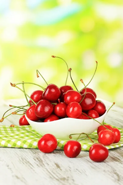 Cherry bessen in kom op houten tafel op lichte achtergrond — Stockfoto