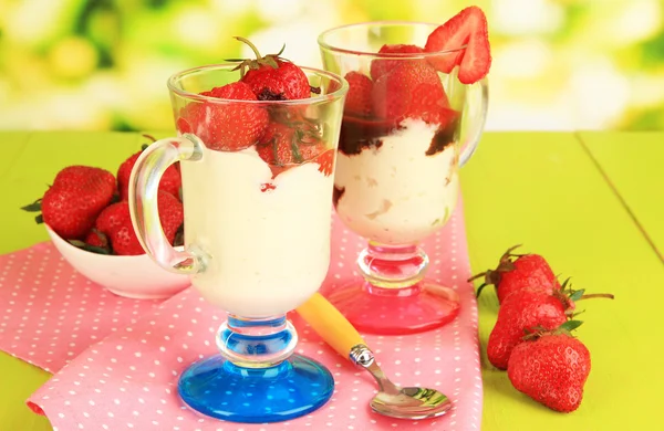 Deliziosi dessert alla fragola in vaso di vetro su tavolo di legno su sfondo naturale — Foto Stock