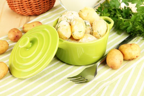 Batatas jovens macias com nata azeda e ervas na panela na mesa de madeira close-up — Fotografia de Stock