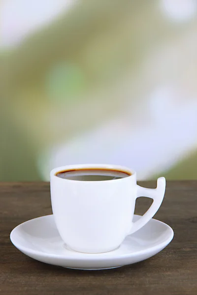 Tasse Kaffee auf Holztisch auf hellem Hintergrund — Stockfoto