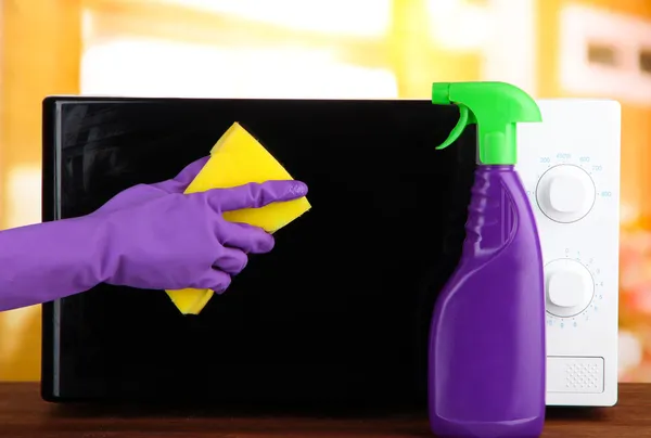 Mikrodalga fırın, parlak zemin temizlik sünger ile el — Stok fotoğraf