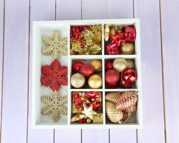 Holzkiste gefüllt mit Weihnachtsschmuck, auf farbigem Holzgrund — Stockfoto