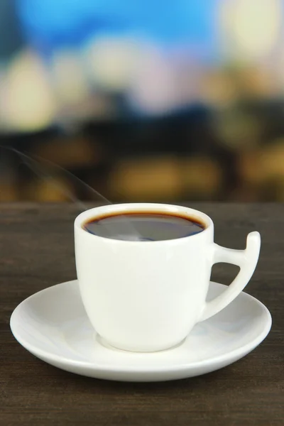 Kopp kaffe på träbord på ljus bakgrund — Stockfoto