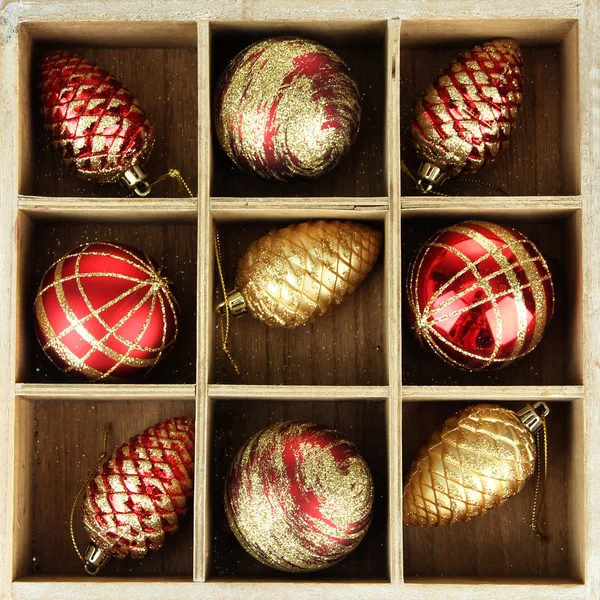 Holzkiste gefüllt mit Weihnachtsschmuck, auf farbigem Holzgrund — Stockfoto