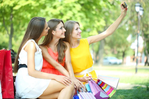 Три красивые девушки фотографируются в летнем парке — стоковое фото